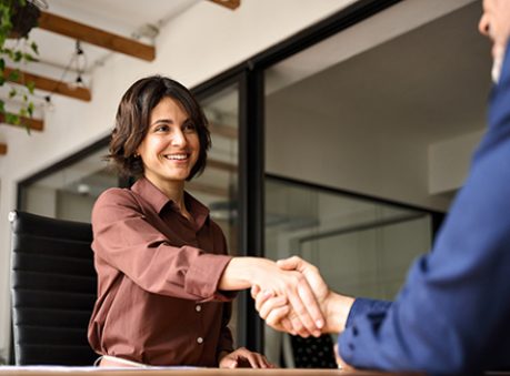 Happy young business woman bank manager handshaking client at meeting. Smiling female hr hiring recruit at job interview, insurance agent, lawyer making contract deal at work with business handshake.